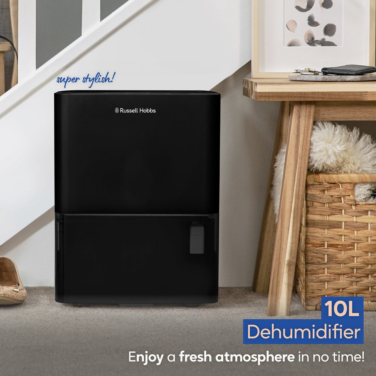 Russell Hobbs 10L black dehumidifier positioned on carpet next to wooden furniture in a modern home interior with "super stylish" text and product badge visible