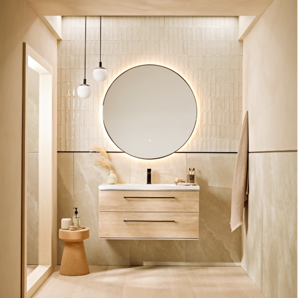 Modern bathroom vanity unit in sand oak finish with white ceramic sink, black tap, and round mirror mounted on beige tiled wall, featuring pendant lighting and minimalist design