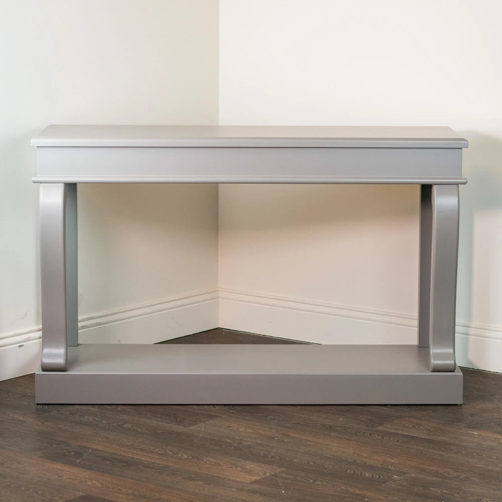 Mink grey Tara Lane Scroll Console Table 130cm with chrome handles and decorative moulding, displayed in a bright interior space on dark wood flooring