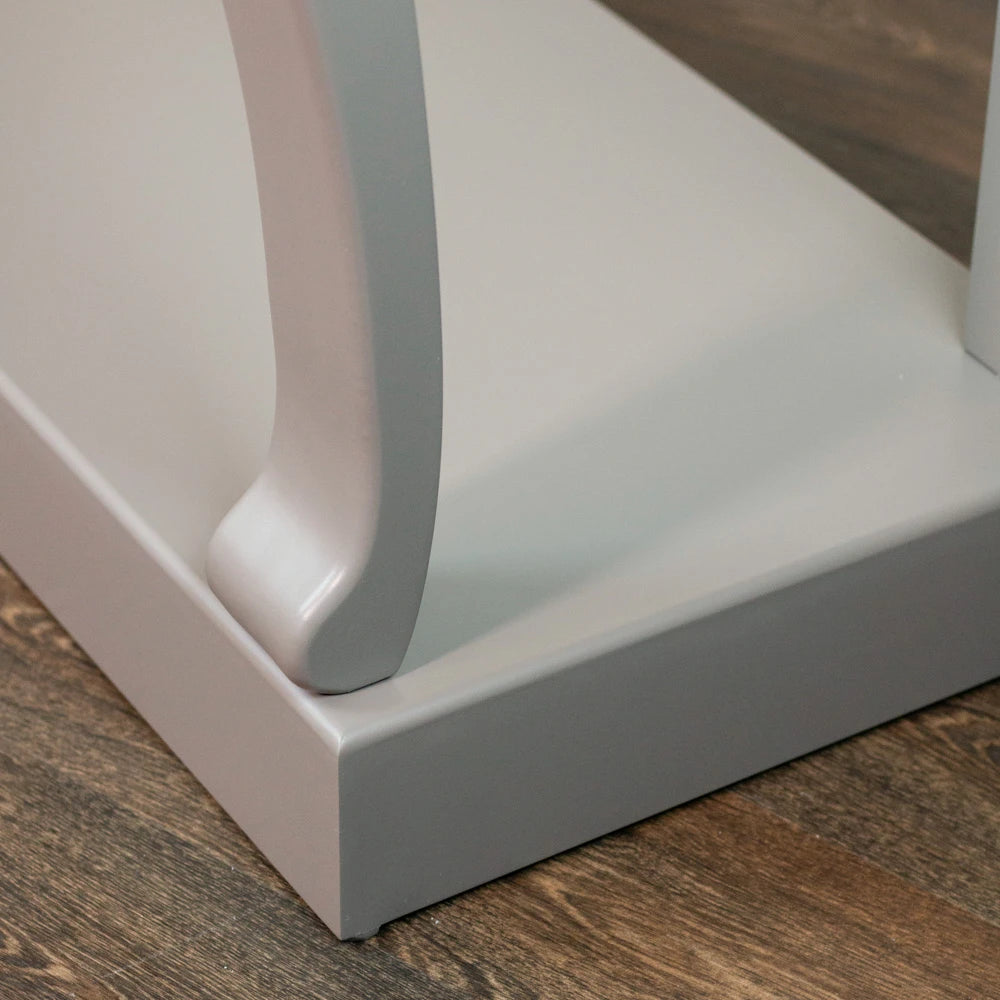 Close-up detail of white modern console table leg showing curved scroll design and glossy finish on wooden floor