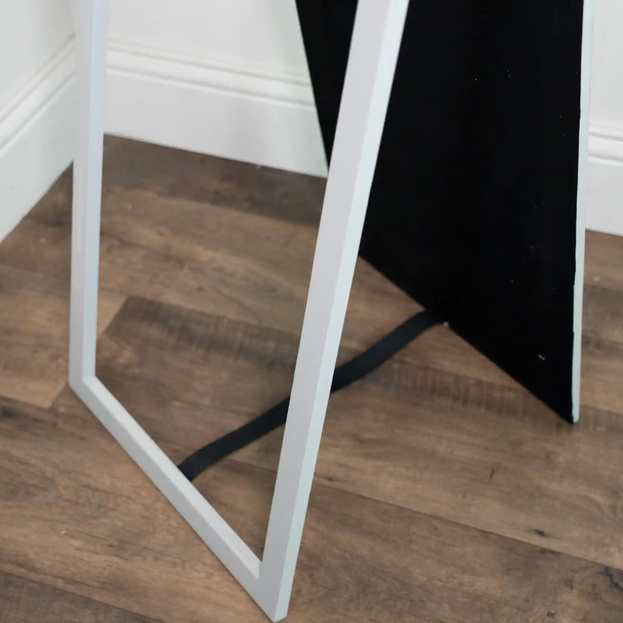 Tara Lane Stepped Arched Floorstanding Mirror in Oyster white with black back panel, 40cm x 170cm, leaning against wooden floor and white wall