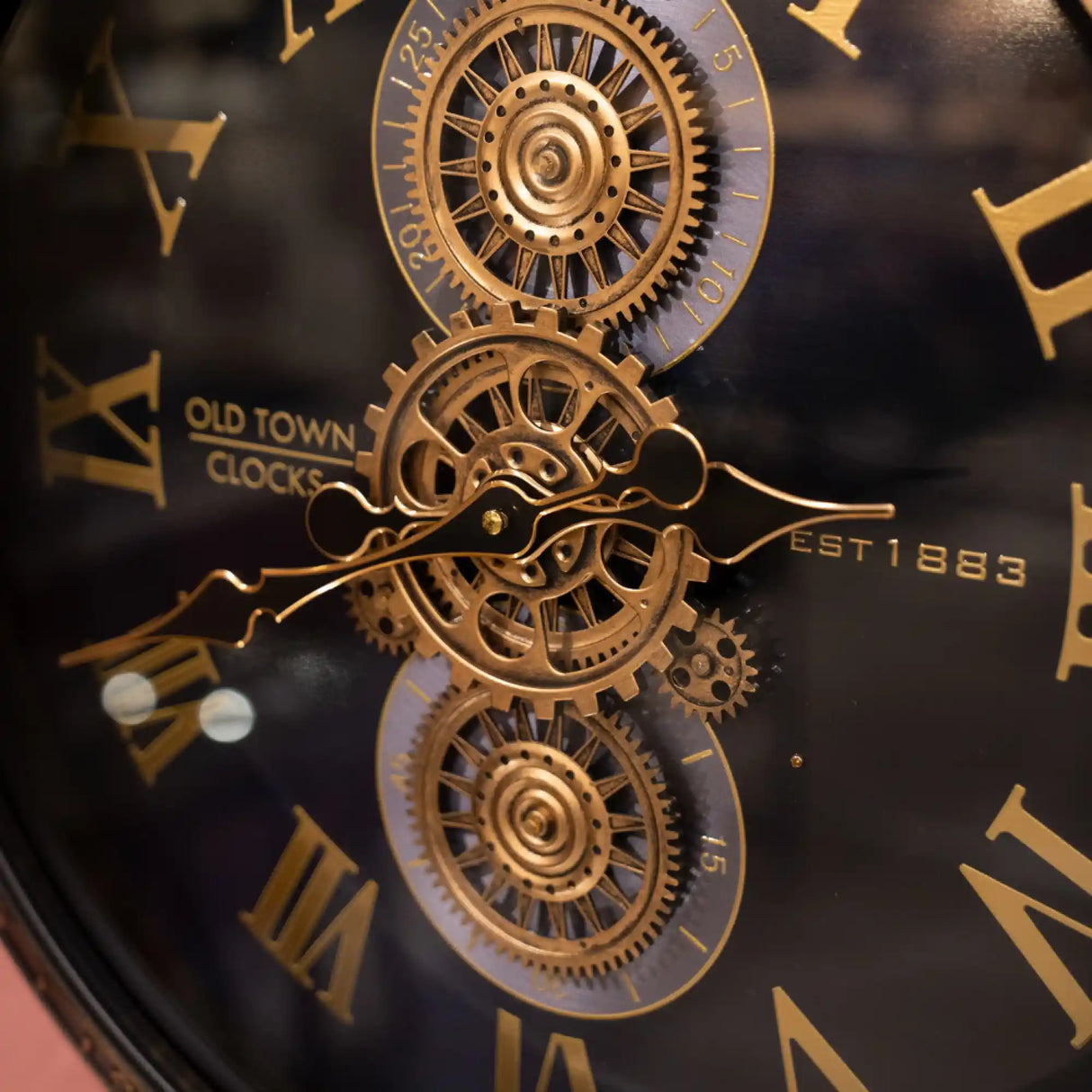Tara Lane Old Town Gears Clock 50cm featuring ornate brass gears and mechanical clock hands on a black face with gold Roman numerals, established 1853