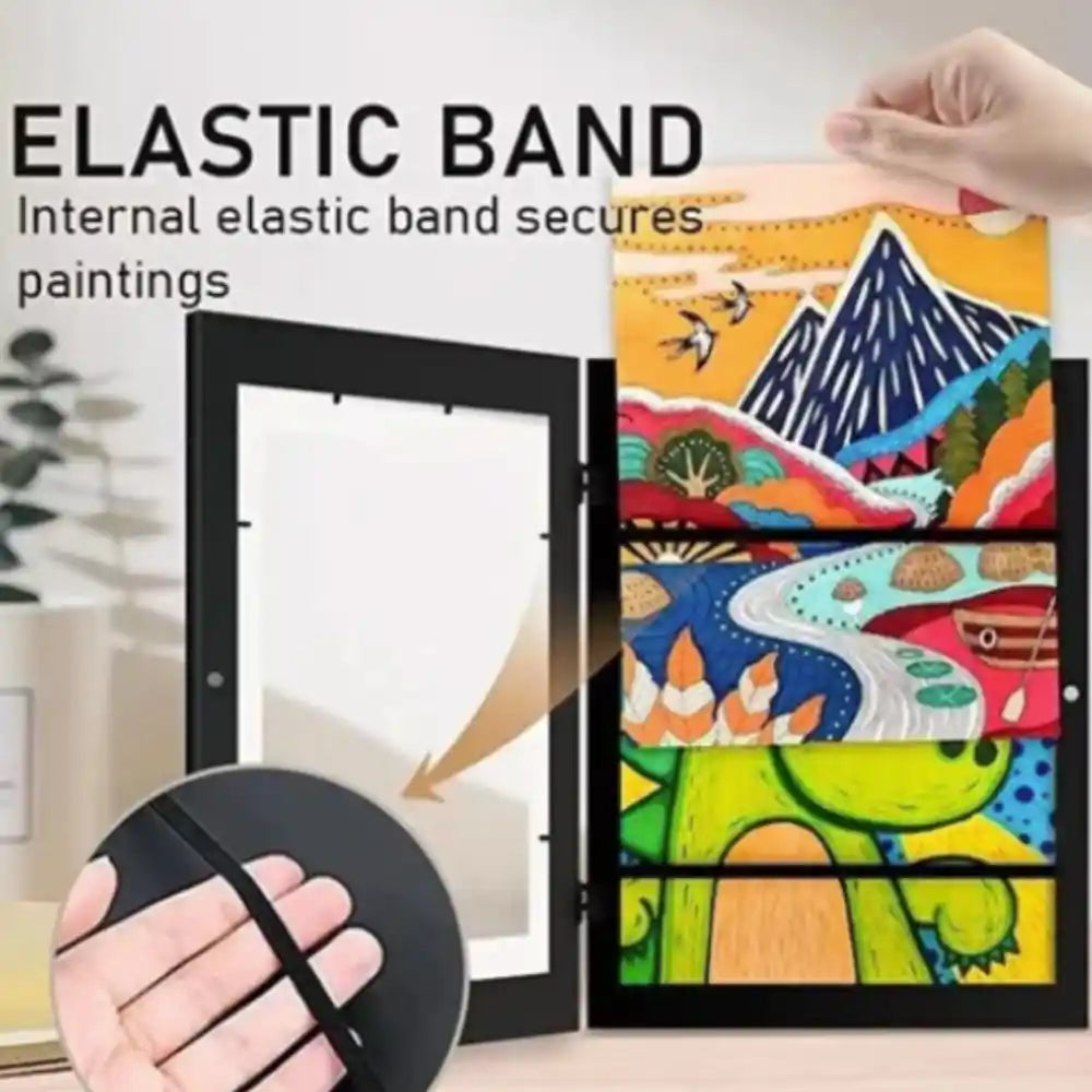 Black MDF artwork frame with elastic band closure displaying colorful children's paintings including mountain landscape, nature scenes and abstract designs, shown with hand demonstrating elastic band feature and sample artwork in background