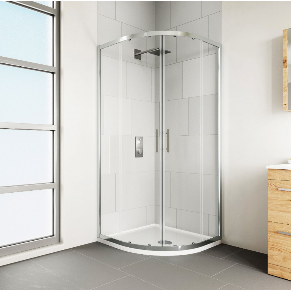 Chrome framed quadrant shower enclosure with curved glass doors and white tray base in modern bathroom with white subway tiles, grey flooring and wooden vanity unit