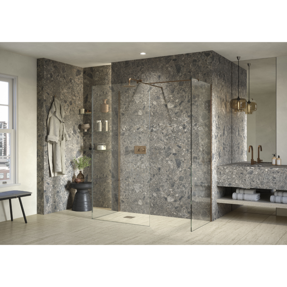 Modern luxury bathroom featuring Flair AYO 8mm glass wetroom panels with brushed brass hardware, grey marble-effect wall panels, light wood flooring, integrated shelving, pendant lighting, and a floating concrete sink vanity