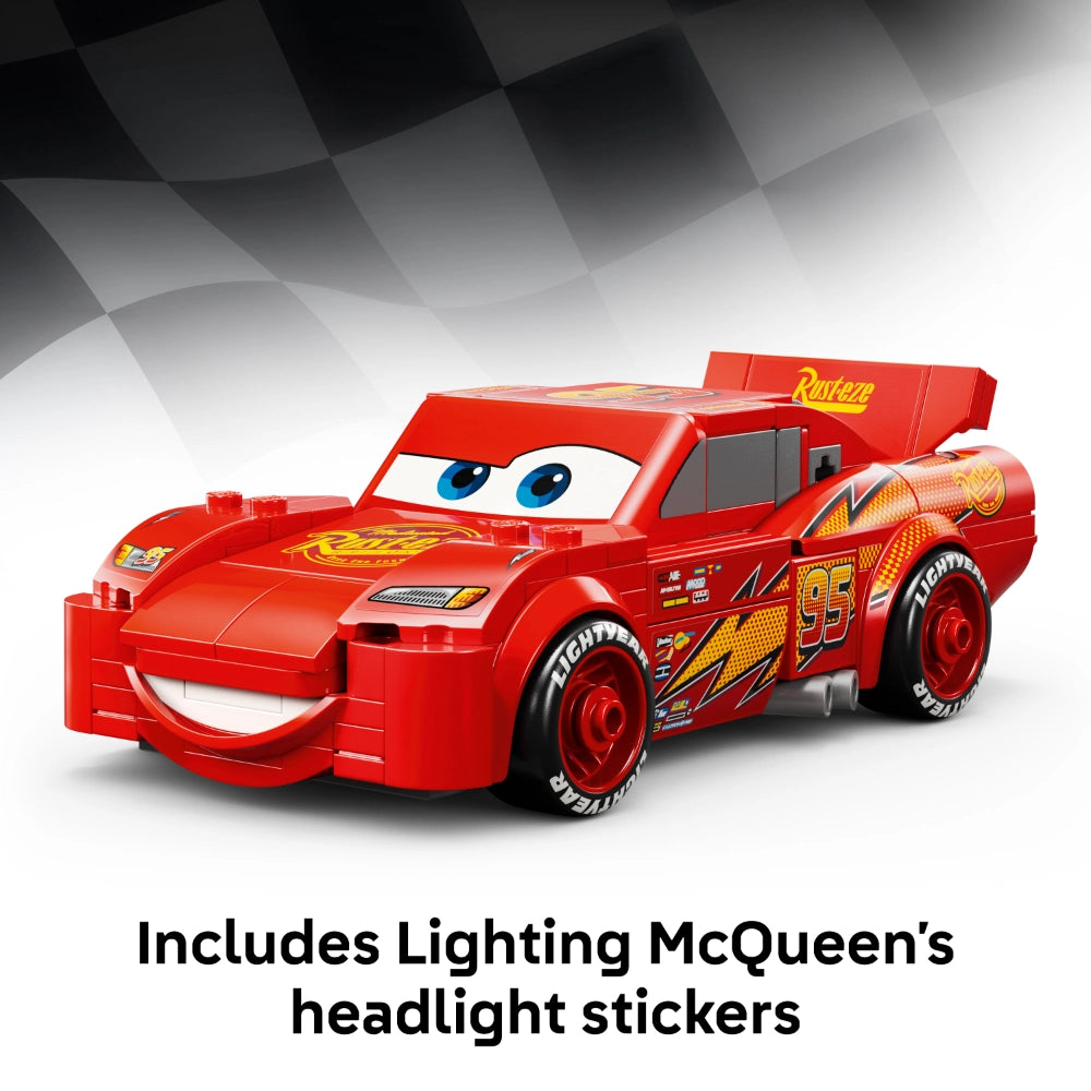 Red LEGO Lightning McQueen car model #77255 with blue eyes, yellow racing details, and black wheels, featuring an openable cargo bed, displayed against a grey checkered background with text indicating included headlight stickers
