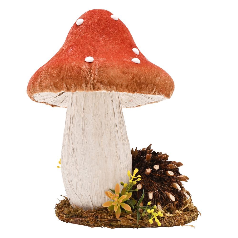 Handmade decorative mushroom ornament with red velvet cap, white polka dots, cream textured stem, and small hedgehog figurine among moss and yellow wildflowers on natural base