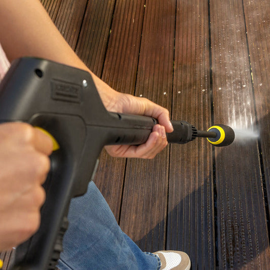 Person using a pressure washer to clean a wooden deck