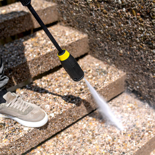 Person using a high-pressure washer to clean concrete steps.