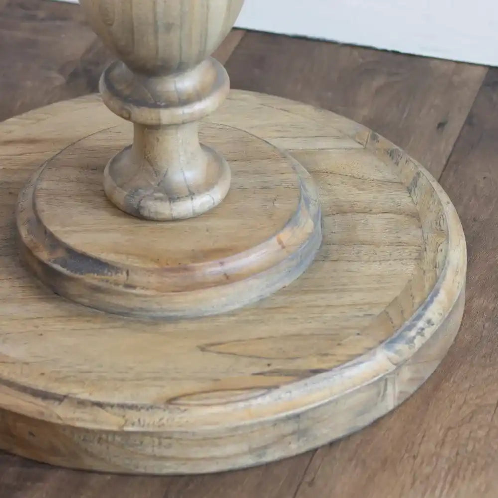 Tara Lane Round Pillar Side Table in natural wood with turned pedestal base, circular top and lower shelf, displayed on wooden floor