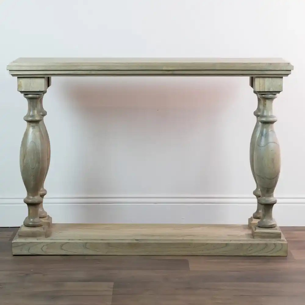 Tara Lane Pillars Console Table 120cm in light grey-green wood finish with turned pedestal legs and shelf base on dark wooden floor