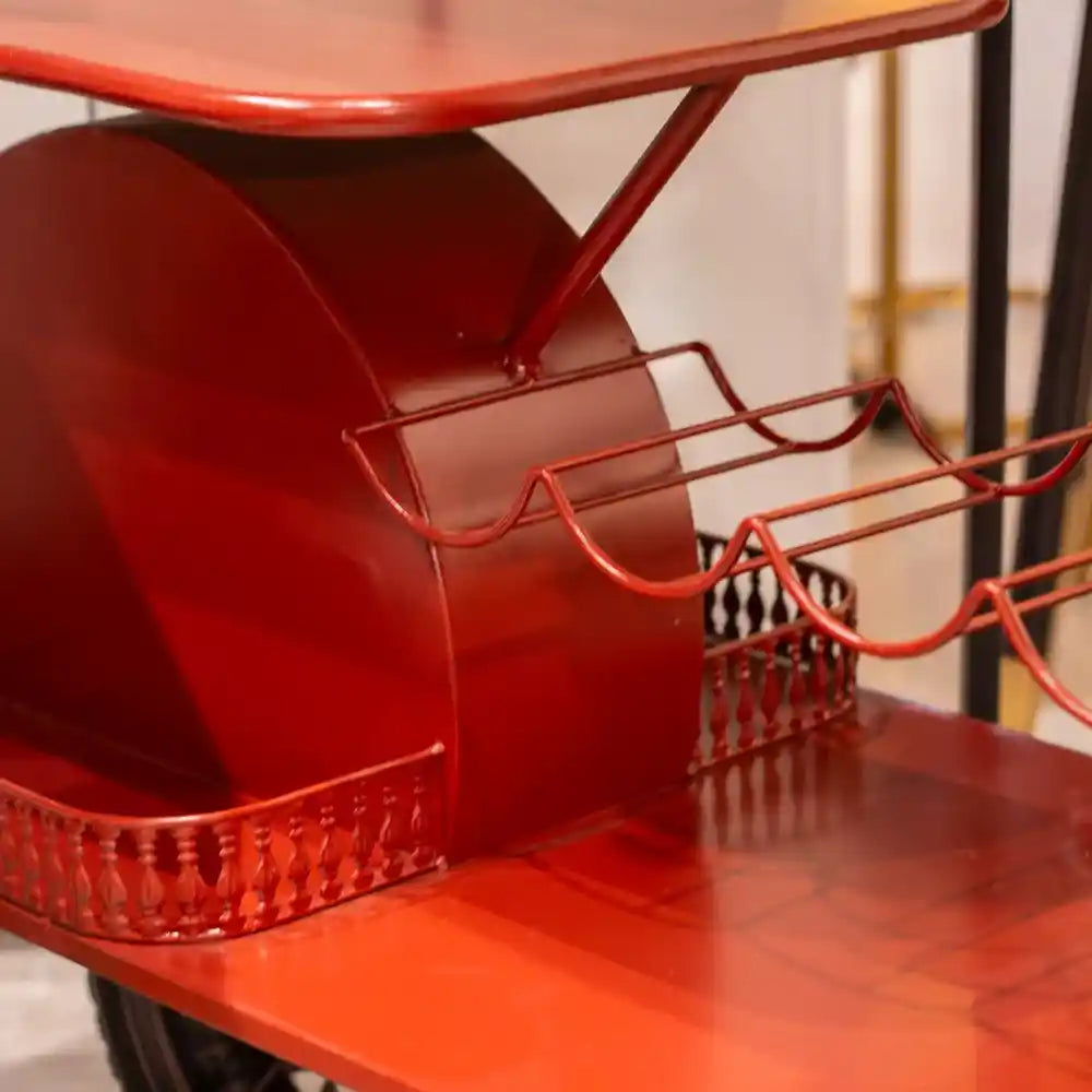Red metal Vespa scooter-shaped wine rack with curved seat back, handlebars, and wire bottle holders displaying wine bottles in an interior setting