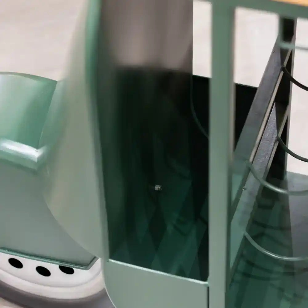 Green metal Vespa scooter-shaped wine rack with white base, featuring three bottle holders and glass shelving, displayed against white background