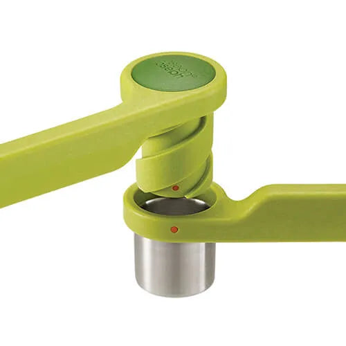 Joseph Joseph Helix Garlic Press in lime green with stainless steel chamber, featuring ergonomic handles and red indicator dots, shown at angle against white background