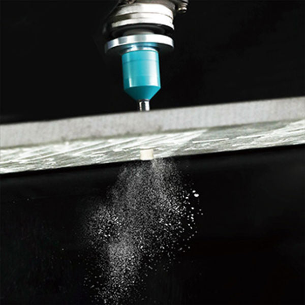 Diamond brazed tile drill bit 6mm with blue coolant reservoir and metal chuck spraying water mist onto wooden surface against black background