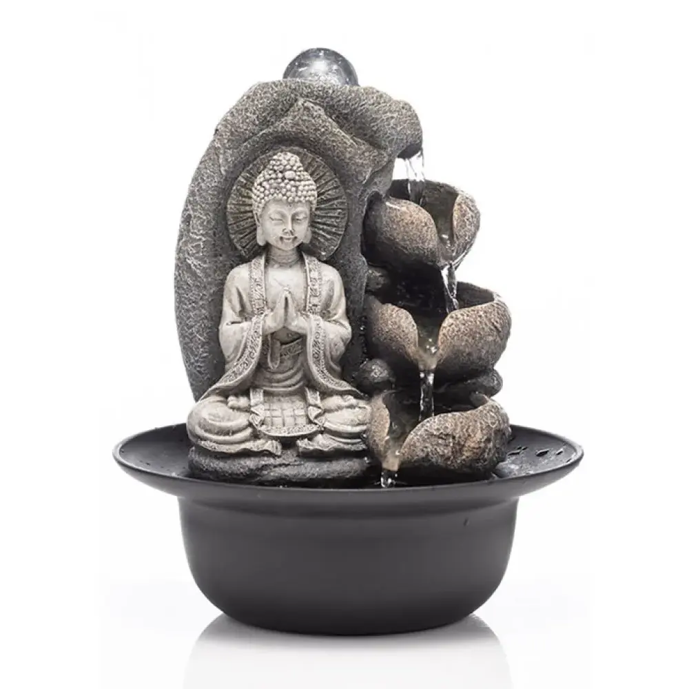 Gray stone Buddha tabletop water fountain with stacked rocks and cascading water feature in black basin with LED light sphere on white background