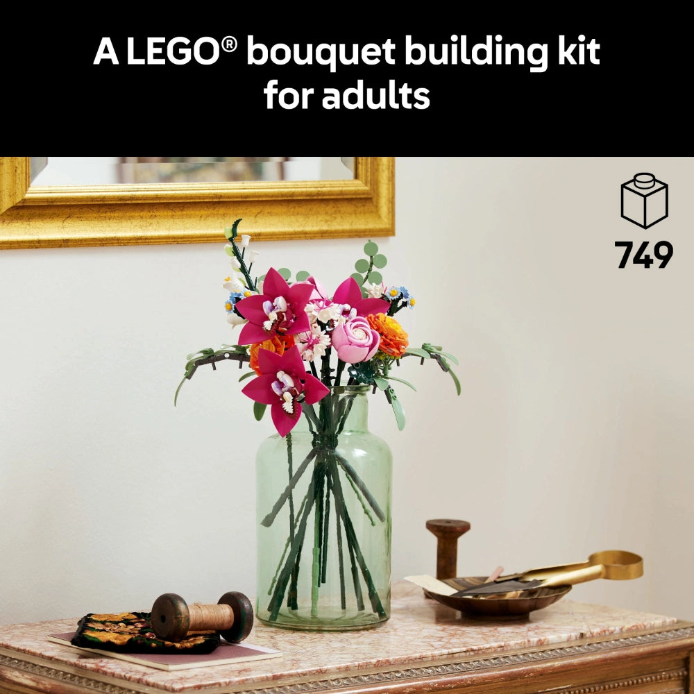 LEGO bouquet building kit for adults featuring pink and red flowers in a green glass vase displayed on a wooden dresser with gold frame and decorative items, 749 pieces