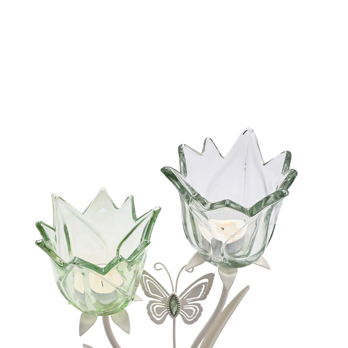 Two green glass tulip-shaped candle holders with white inner petals on a matte off-white base, accompanied by a decorative butterfly garden stake featuring green and white enamel detailing
