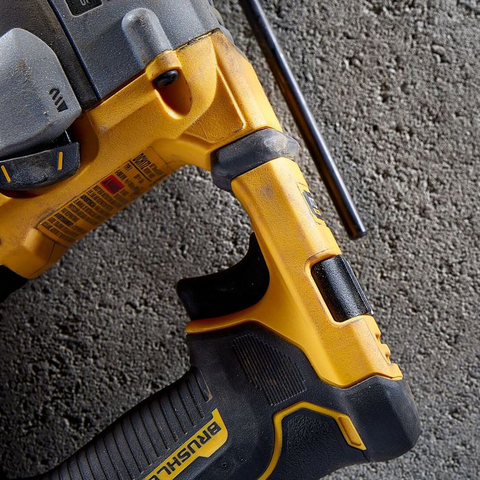 DeWalt DCH172P2 compact yellow and black SDS Plus rotary hammer drill shown from top angle on concrete surface with charging cable visible