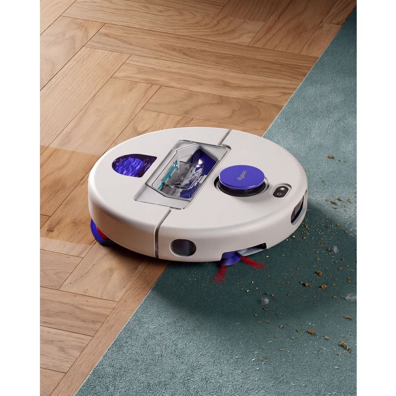 Dyson R2 Nurovi robot vacuum with white and blue design on herringbone wooden floor and gray carpet, showing dustbin compartment and control panel