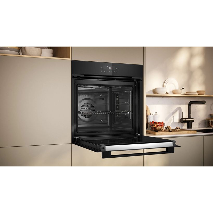 Black built-in single oven with pyrolytic self-cleaning function integrated into beige kitchen cabinetry with open shelving displaying dishes and a black tap