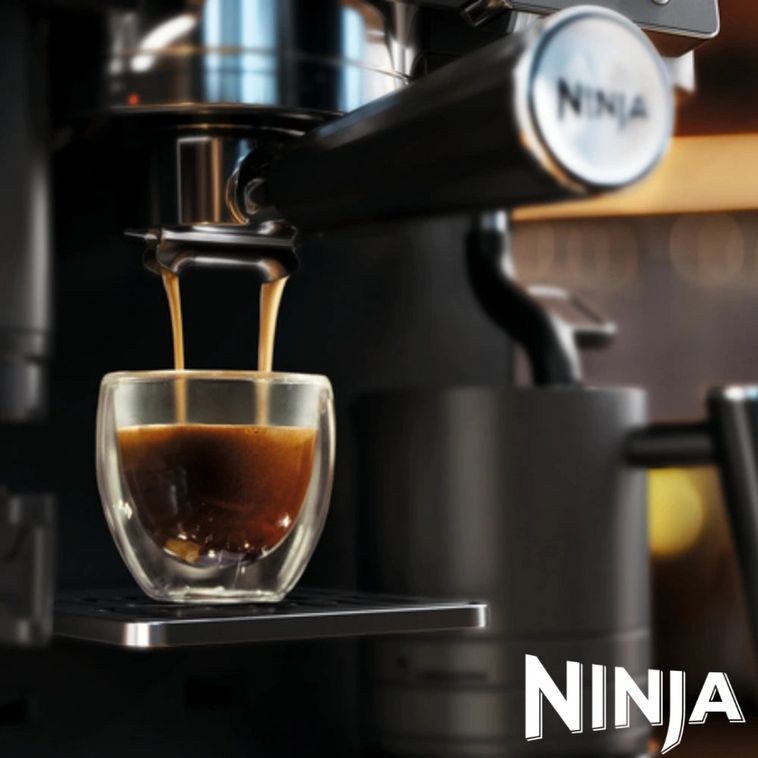 Ninja Luxe Café Premier Series black coffee machine dispensing espresso into a clear double-walled glass cup, with chrome accents and Ninja branding visible