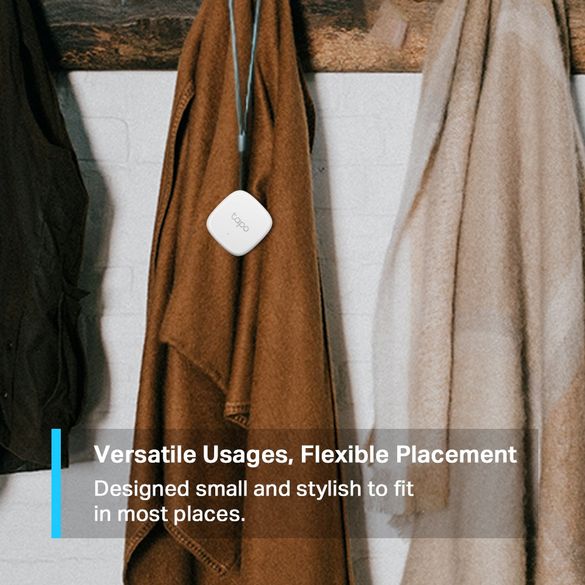 TP-Link Tapo T310 smart sensor hanging from a blue cord on brown and beige fabric scarves draped over a white chair, showing compact white square device design for temperature and humidity monitoring
