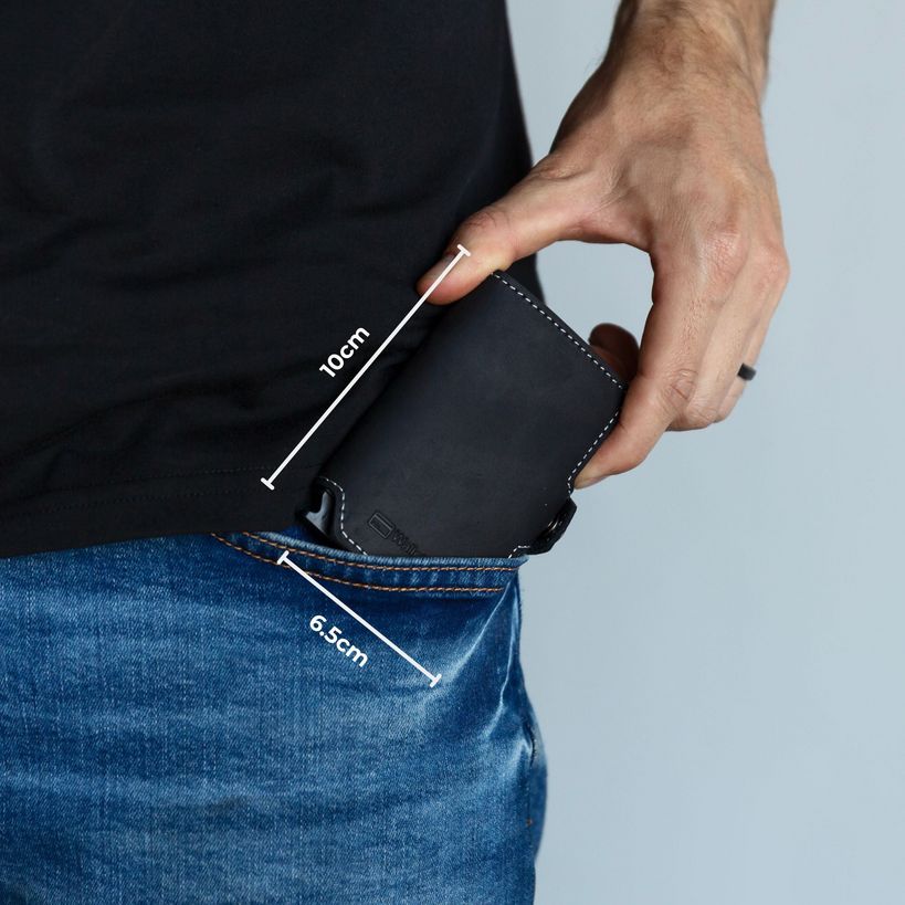 Man holding Wallet Junkie Pro Slim midnight black leather wallet showing dimensions of 10cm height and 6.5cm width, demonstrating compact slim design suitable for up to 9 cards, worn at jeans pocket