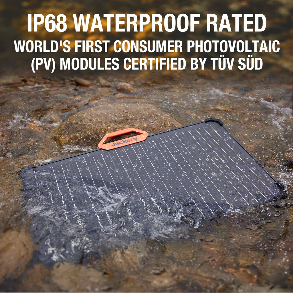 Jackery SolarSaga 80W portable solar panel with orange carry handle partially submerged in water demonstrating IP68 waterproof rating, certified by TÜV SÜD, featuring dark solar cells with water droplets on surface