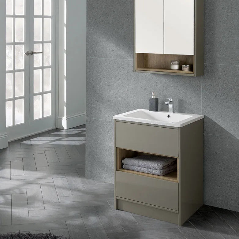 Modern taupe floor-standing bathroom vanity unit with white ceramic sink, chrome tap, integrated open shelf with grey towels, matching wall-mounted mirror cabinet, grey textured tile walls and herringbone wood-effect floor tiles