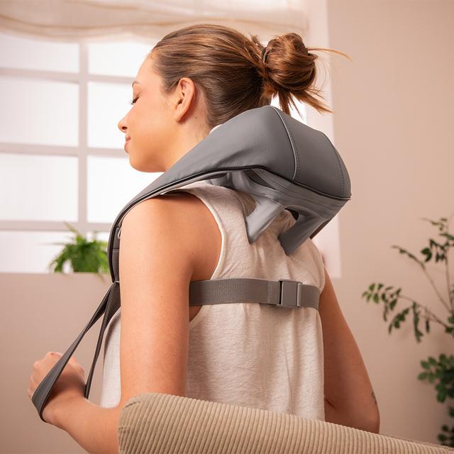 Woman using a neck and shoulder massager in a home setting