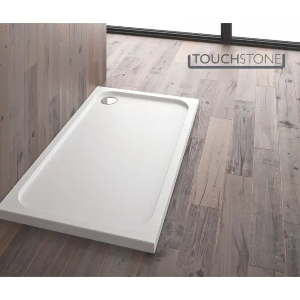 White rectangular shower tray with curved corners on grey wood-effect bathroom flooring, Merlyn Touchstone branding visible on wall behind