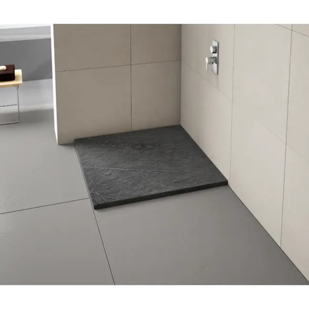 Modern bathroom shower enclosure featuring a dark grey slate-effect rectangular shower tray with chrome fixtures on cream tile walls and light grey floor tiles