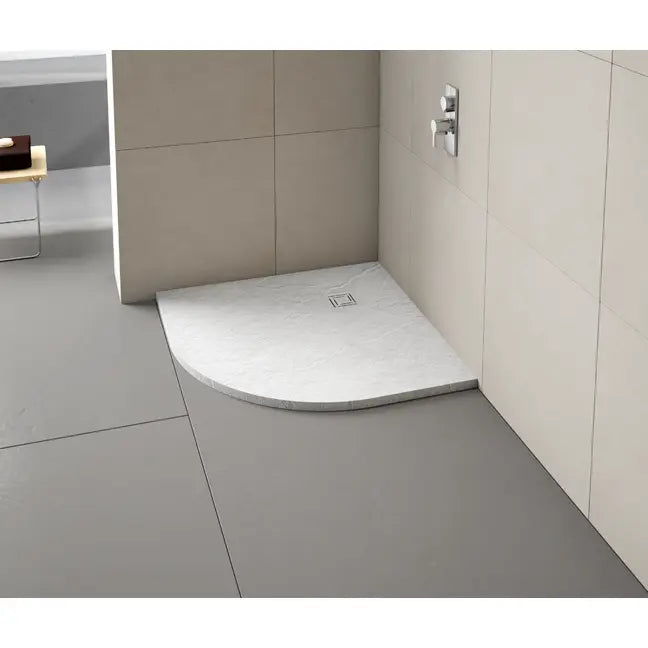White curved quadrant shower tray with integrated drain installed in modern bathroom with beige tile walls and grey floor