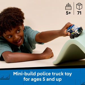 Child holding a small LEGO police truck toy with blue and white colors above a green curved LEGO brick structure, demonstrating the mini-build police vehicle set for ages 5 and up containing 71 pieces