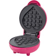 Pink heart-shaped waffle maker with non-stick grey cooking plates, open position showing grid pattern molds, compact countertop design with handle