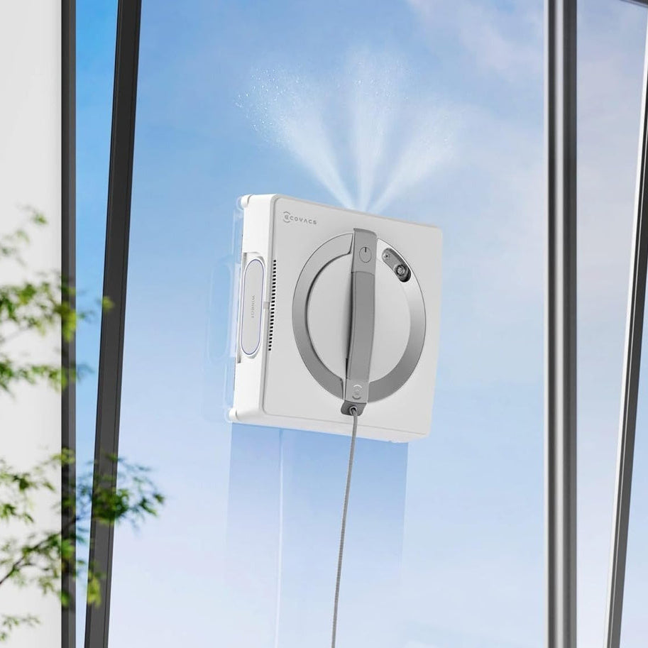 Window cleaning robot in front of a glass door with a clear blue sky.
