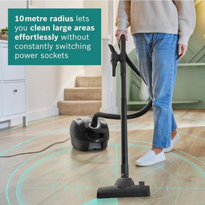 Person using a vacuum cleaner with text about its 10-metre radius cleaning capability.