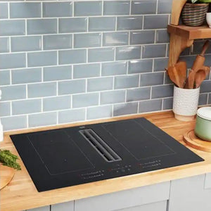 Beko black vented extractor induction hob installed in modern kitchen with grey subway tile backsplash, wooden countertop, white cabinetry and kitchen accessories