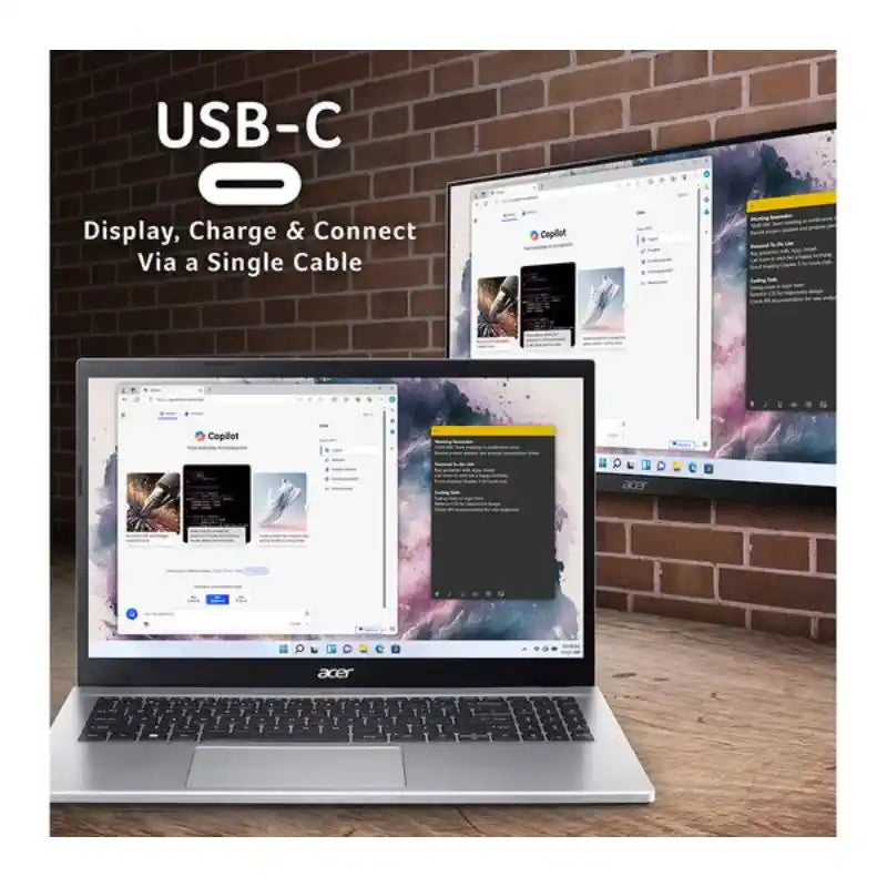 Acer Aspire Go 15 silver laptop displaying dual monitors via USB-C connection, showing Copilot webpage on screen, positioned on wooden desk against brick wall background