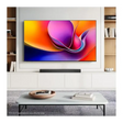 Hisense A6Q 65 inch 4K Smart TV mounted on white wall unit with wooden shelving displaying vibrant colorful abstract wallpaper on screen, black soundbar below, white coffee table with wooden bowl and books in modern living room setting