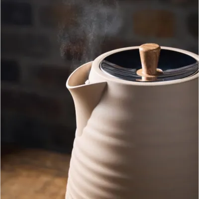 Morphy Richards Clay Felspar 1.7 litre jug kettle in cream white with wooden handle and lid finial, steam rising from spout, shown against blurred kitchen background