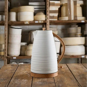 Morphy Richards Clay Flint white jug kettle with wooden handle and base displayed on wooden table against blurred shelving background