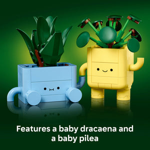 LEGO Happy Plants 10349 set featuring a blue brick-built planter with baby dracaena plant and red-handled tools, and a yellow brick-built planter with baby pilea plant and articulated green arms holding small spheres and tools, displayed against a green gradient background