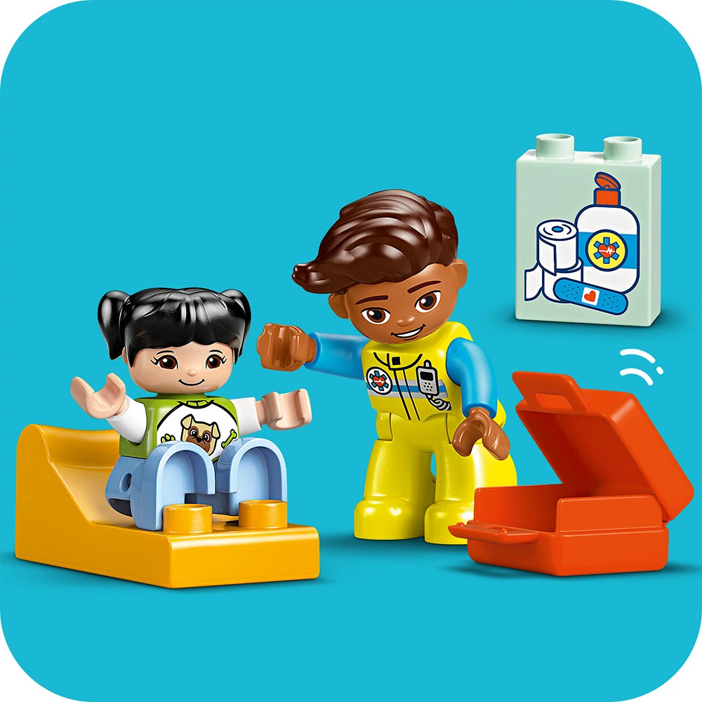 LEGO Duplo ambulance and driver set featuring a yellow ambulance vehicle with blue details, a child figure in green and white clothing, a healthcare worker figure in bright yellow uniform with brown hair, and a white medical supply brick with first aid imagery on a turquoise background