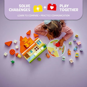 Overhead view of a child playing with LEGO Bluey's Family House set, featuring a colorful orange and green brick house structure, memory game wheel, minifigures, and various building pieces on a purple background with text highlighting challenge-solving and cooperative play features
