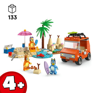 LEGO Bluey's Beach & Family Car Trip set 11202 containing 133 pieces with orange vehicle, blue and orange minifigures, pink umbrella, palm tree, sandcastle structures, surfboard and beach accessories on sand-coloured base with water feature