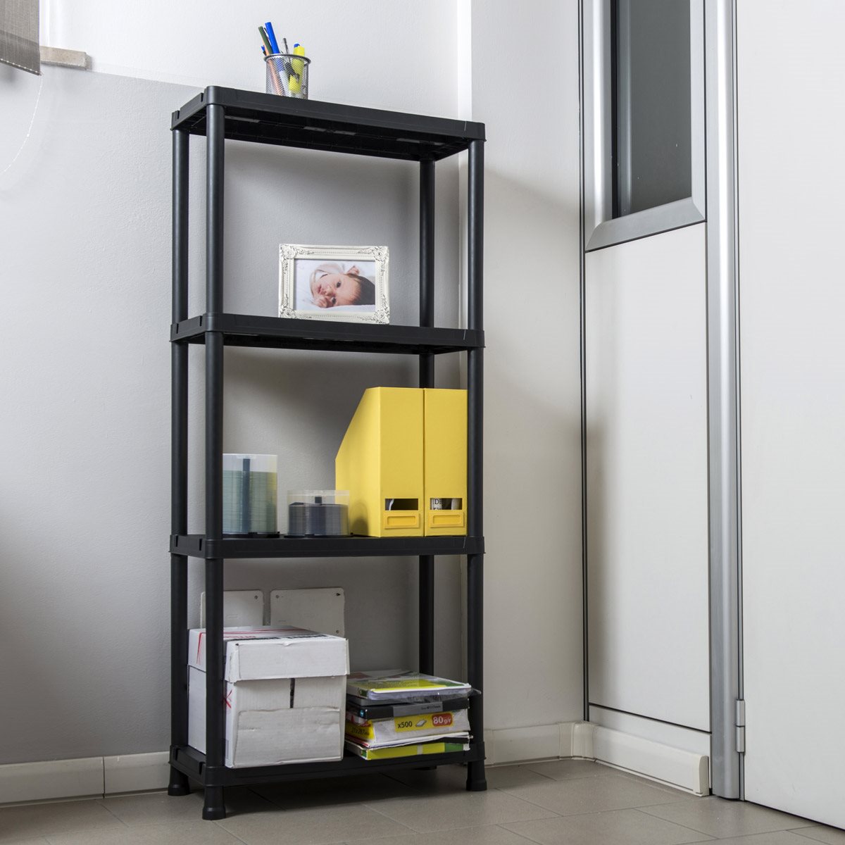 Black metal shelf with various items against a white wall