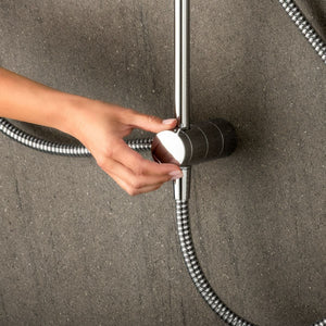 Hand holding a shower head against a gray wall