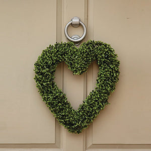 Heart-shaped boxwood topiary wreath in vibrant green hanging on a cream-coloured door with a silver ring knocker, 40cm decorative garden ornament